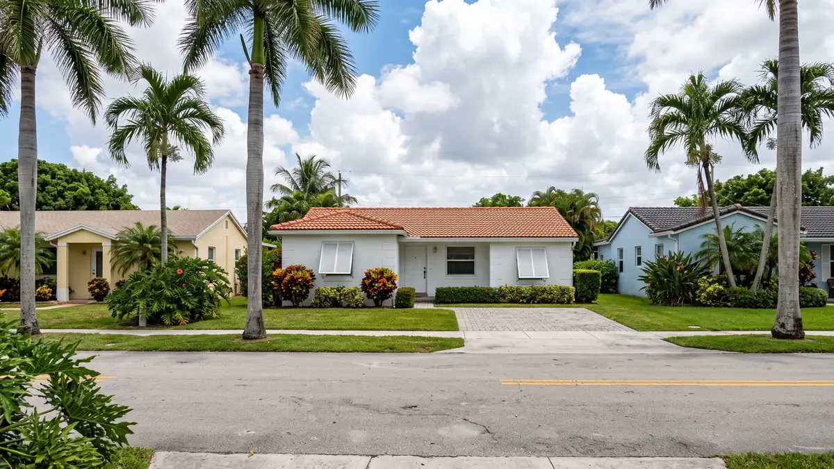 White block home with a terracotta tile roof between pastel neighbours and royal palms — slab leak detection in Homestead, FL