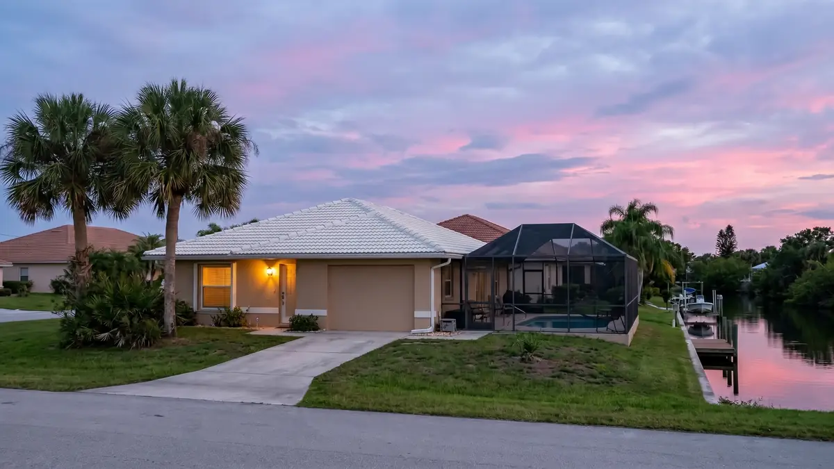 Stucco home at dusk with a screened pool cage beside a canal — slab leak detection in Summerfield, FL